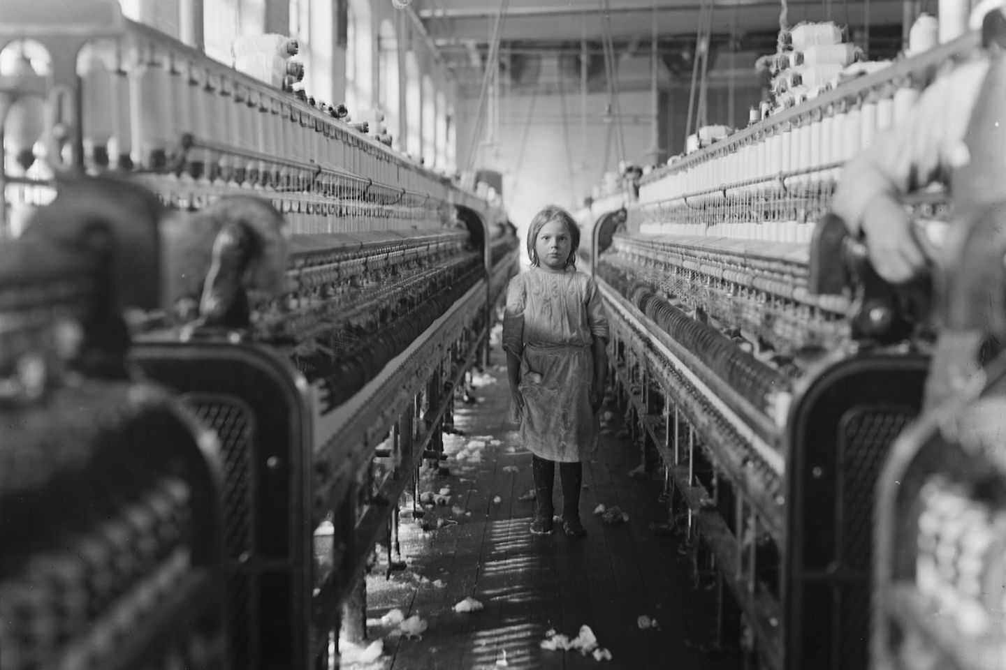Ein Mädchen arbeitet im Jahr 1908 in einer Spinnerei.