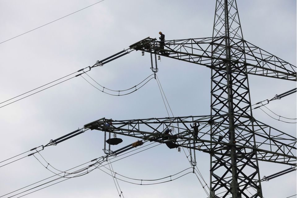 A worker performs maintenance work on a electricity transmission pylon near the gas-fired power plant, operated by Uniper SE, in Irsching, Germany, on Wednesday, July 7, 2021. Germany has an opportunity to phase-out coal power plants almost a decade ahead of schedule -- but it will require a fleet of natural gas plants to do it, a new study by Wartsila Oyj shows. Photographer: Michaela Handrek-Rehle/Bloomberg