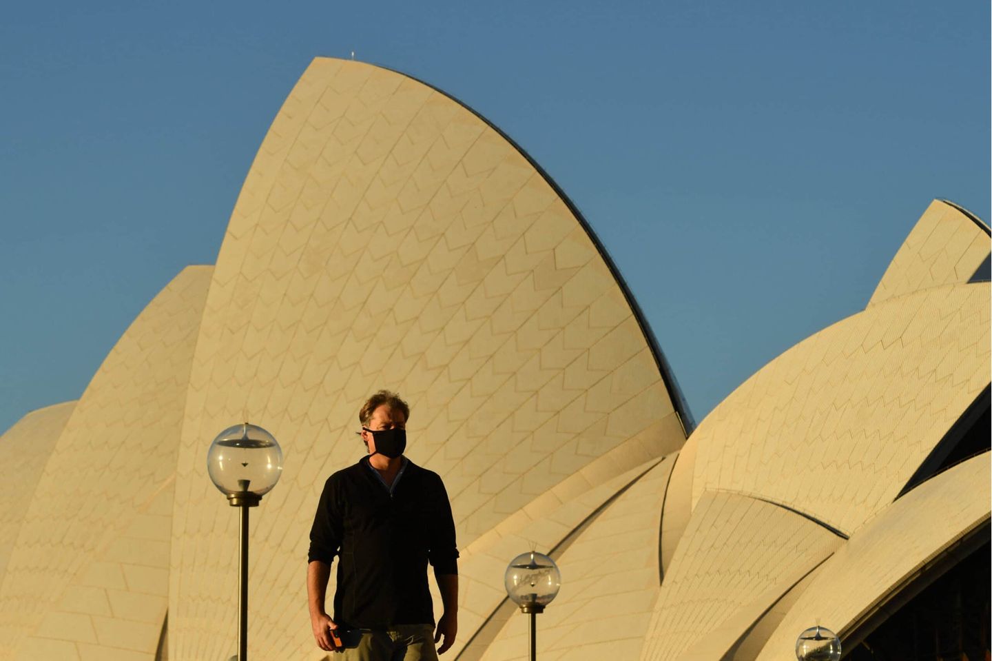 NSW CORONAVIRUS COVID19, A pedestrian walks past the Sydney Opera House at sunset in Sydney, Friday, August 6, 2021. NSW recorded 291 new locally acquired cases of COVID-19 in the 24 hours to 8pm last night. ACHTUNG: NUR REDAKTIONELLE NUTZUNG, KEINE ARCHIVIERUNG UND KEINE BUCHNUTZUNG SYDNEY NSW AUSTRALIA PUBLICATIONxINxGERxSUIxAUTxONLY Copyright: xMICKxTSIKASx 20210806001564769600