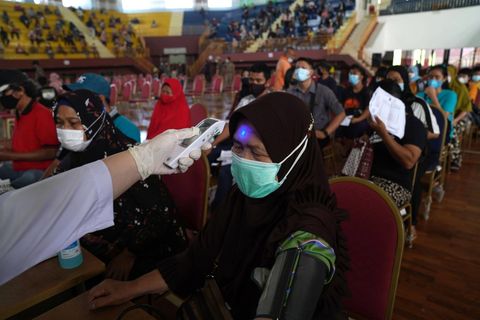 A member of the public gets her temperature checked at a vaccination center in Jakarta, on Aug. 4.