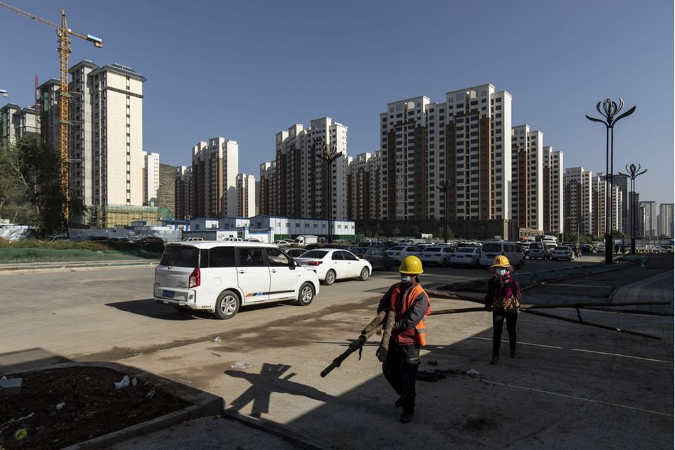 Workers carry wooden poles near apartment blocks under construction in the Nanchuan area of Xining, Qinghai province, China, on Tuesday, Sept. 28, 2021. China has urged financial institutions to help local governments stabilize the rapidly cooling housing market and protect the rights of some homebuyers, another signal that authorities are worried about fallout from the debt crisis at China Evergrande Group. Photographer: Qilai Shen/Bloomberg