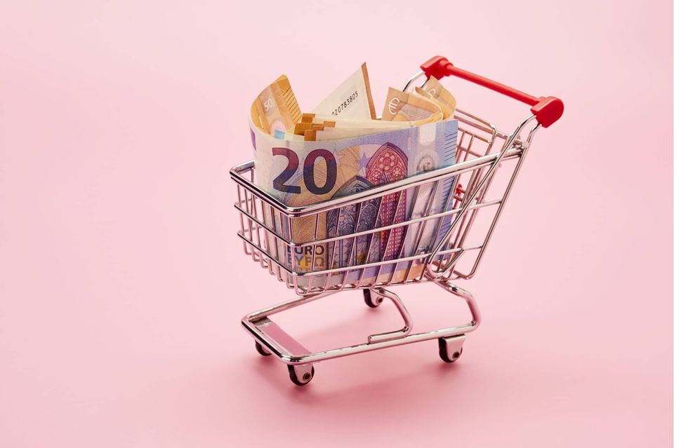 Still life of shopping cart and Euro notes on pink background