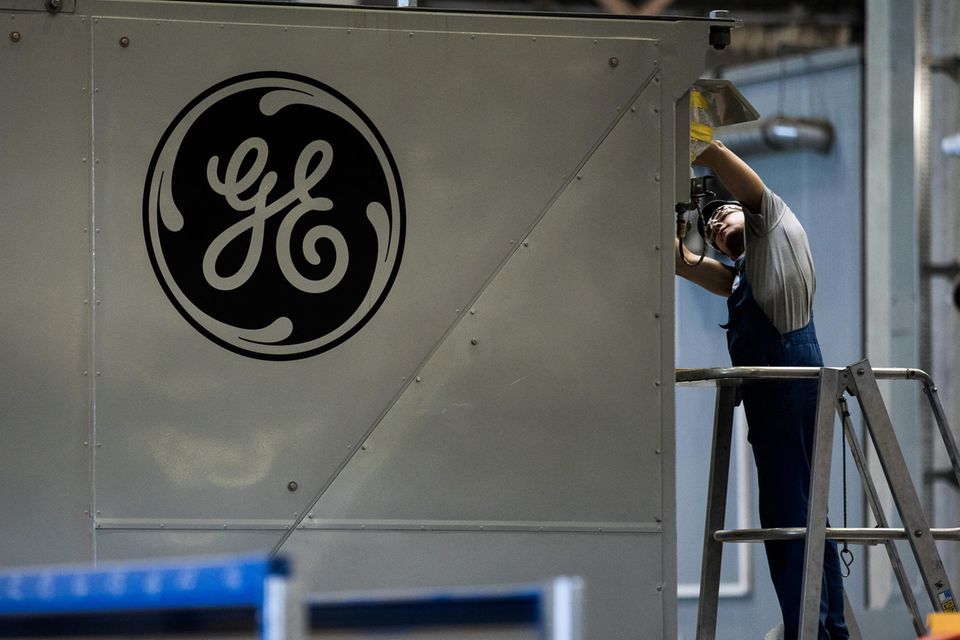 A GE logo sits on a panel as an employee works inside the General Electric Co. power plant in Veresegyhaz, Hungary, on Tuesday, June 13, 2017. General Electric won approval on Monday from the U.S. Justice Department to combine its oil and gas business with Baker Hughes Inc. Photographer: Akos Stiller/Bloomberg via Getty Images