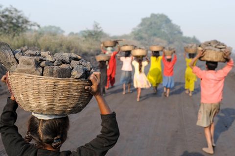 Kinder sammeln Kohle auf einer Abraumhalde am Rande eines Kohletagebaus zum Verkauf auf dem Markt in Jharia Jharkhand
