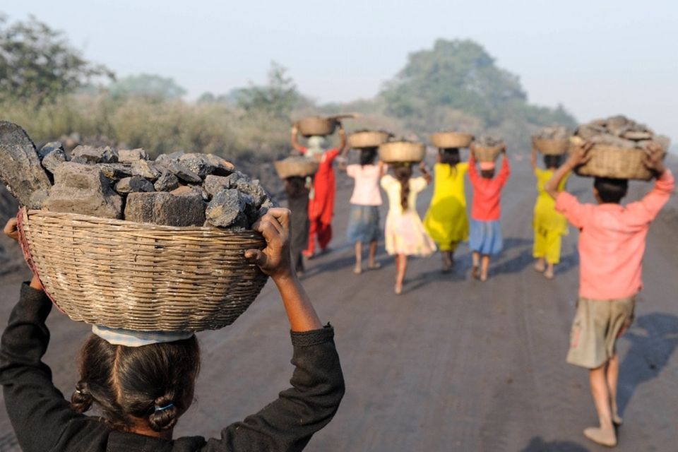 Kinder sammeln Kohle auf einer Abraumhalde am Rande eines Kohletagebaus zum Verkauf auf dem Markt in Jharia Jharkhand