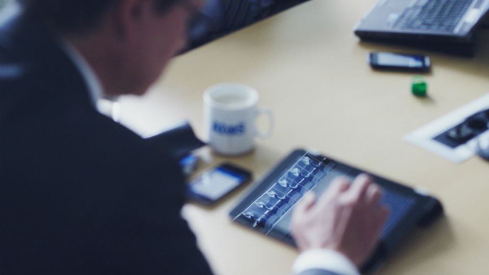 Atos-Deutschlandchef Winfried Holz sitzt an seinem iPad und organisiert über das Netzwerk blueKiwi die Vorbereitung für ein Treffen seines Verbandes Bitkom
