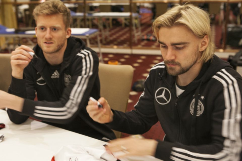 Die Spieler André Schürrle und Marcel Schmelzer signieren im Akkord Trikots
