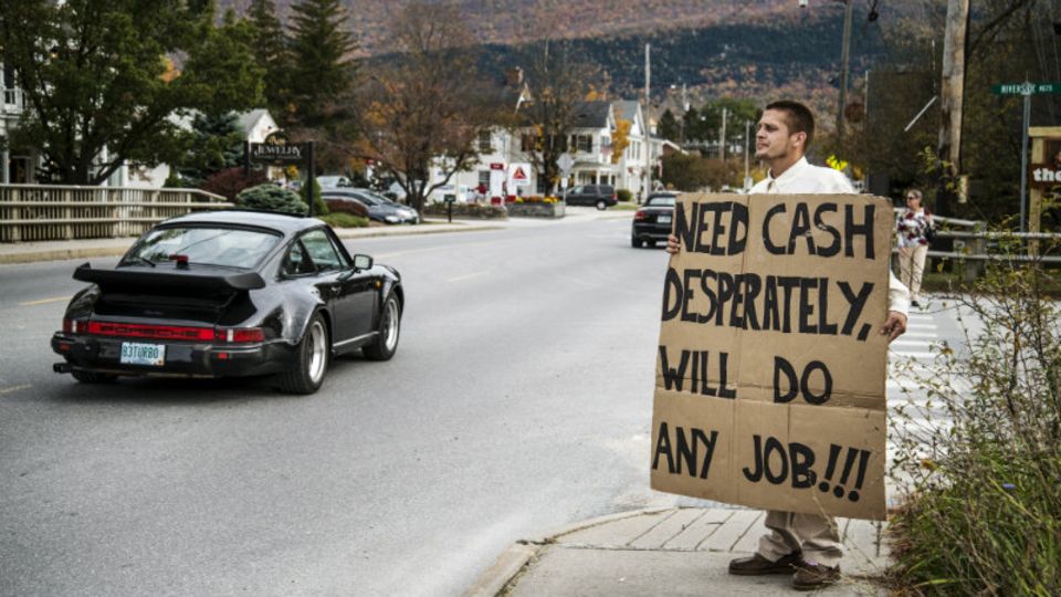 Der Arbeitslose hält ein Schild hoch, während ein Porsche vorbeibraust: „Brauche dringend Geld, werde jede Arbeit machen.“ Der Mann steht an einer Kreuzung in Manchester Village, einer reichen Kleinstadt im US-Bundesstaat Vermont