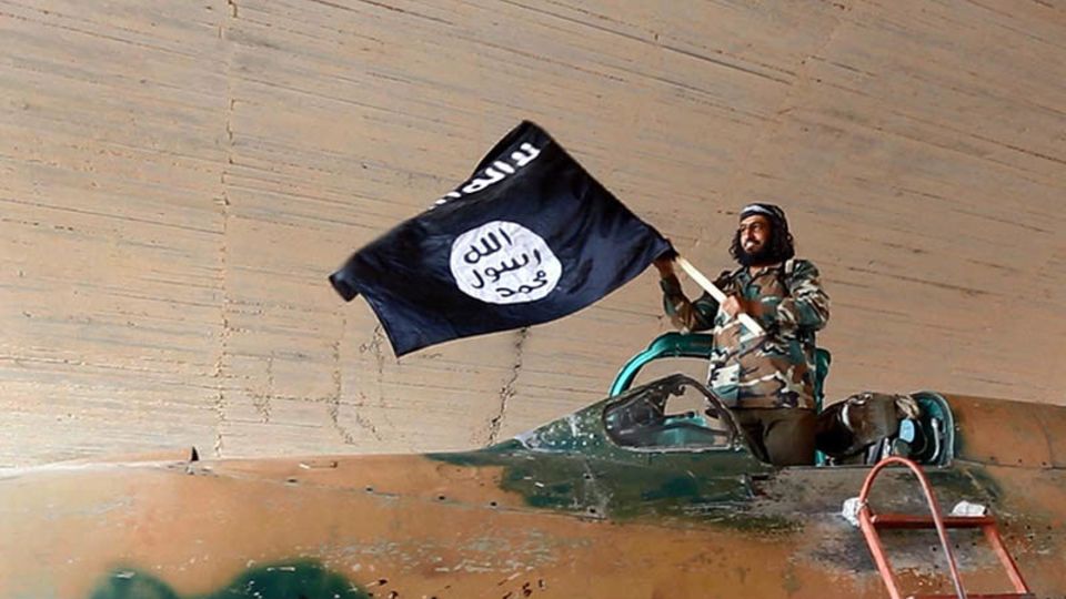 Ein IS-Kämpfer schwenkt in einem erbeuteten Jagdflugzeug die Fahne der Terroristen