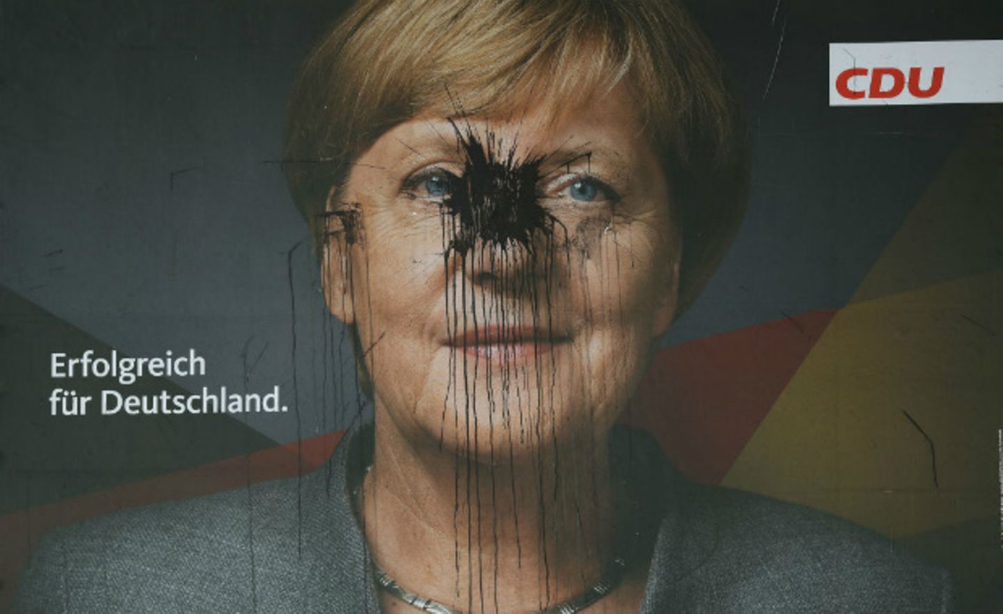 Ein von einem Fabrbbeutel getroffenes Wahlplakat von Angel Merkel