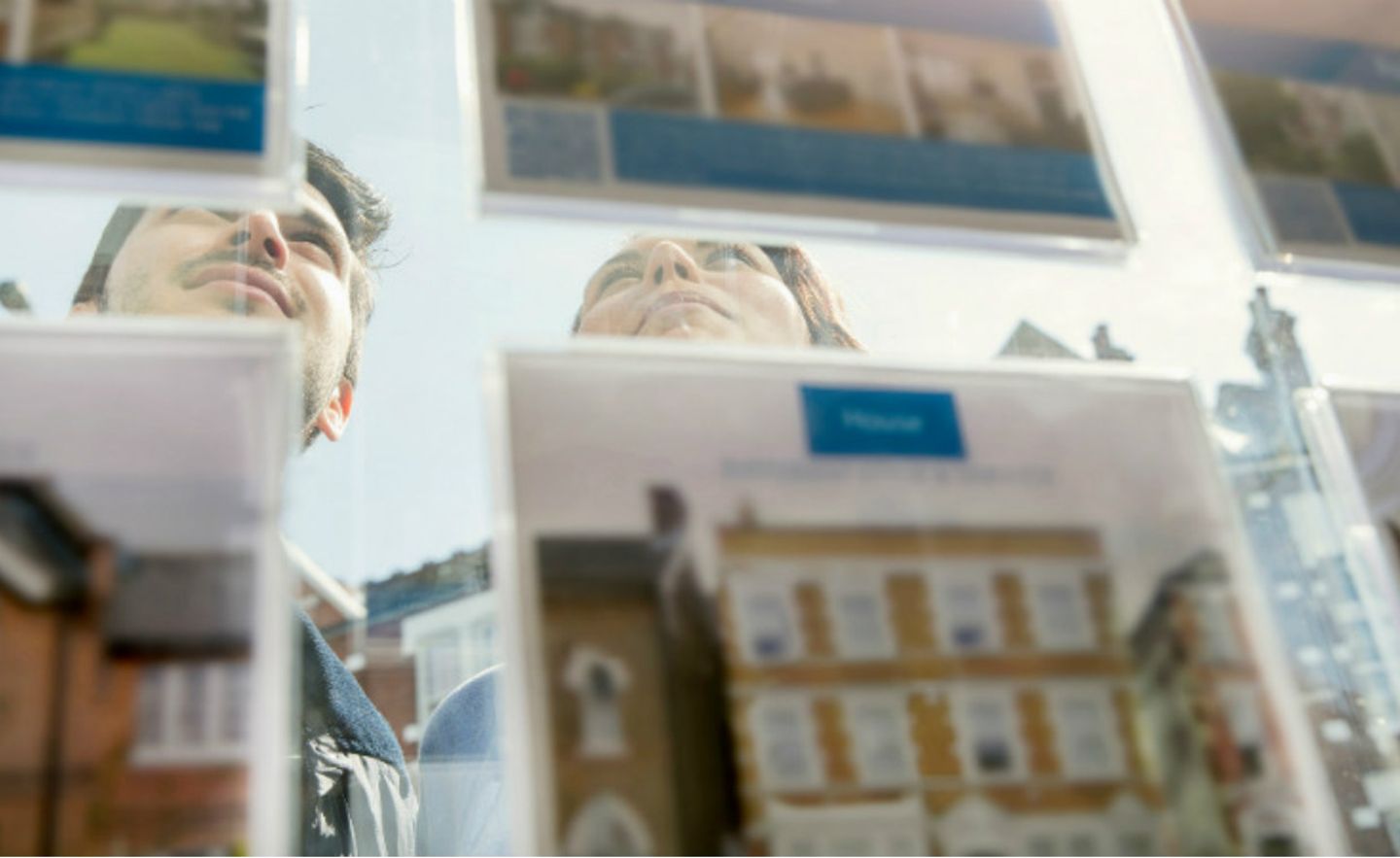 Ein junges Paar studiert Immobilienanzeigen in einem Schaufenster