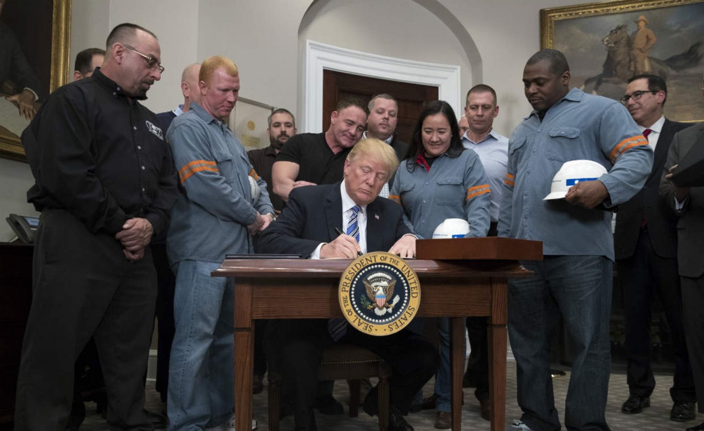 Umringt von amerikanischen Stahlarbeitern unterzeichnet US-Präsident Trump das Dekret zur Verhängung von Strafzöllen auf Stahl- und Aluminiumimporte