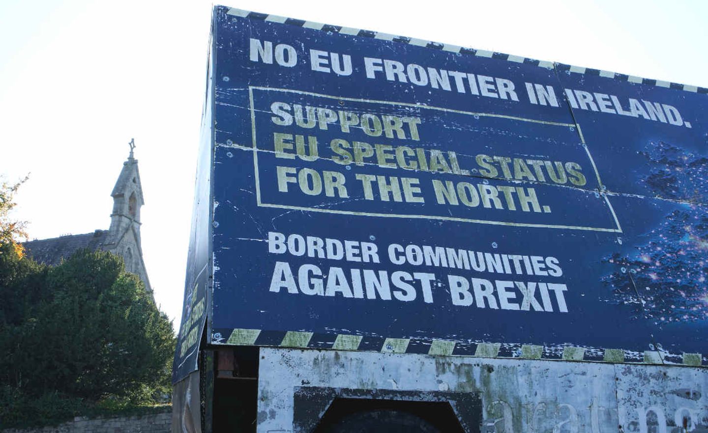 In der an Nordirland angrenzenden irischen Ortschaft Carrickcarnan liegt der lokale Friedhof auf irischem Gebiet, die dazugehörige Kirche steht auf der nordirischen Seite. Die Sorge vor den Folgen eines „No Deals“ in den Brexit-Verhandlungen sind hier besonders ausgeprägt. Vor der Kirche haben Brexit-Gegner der nordirischen Grenzregionen einen Anhänger aufgestellt: „Keine EU-Grenze in Irland“