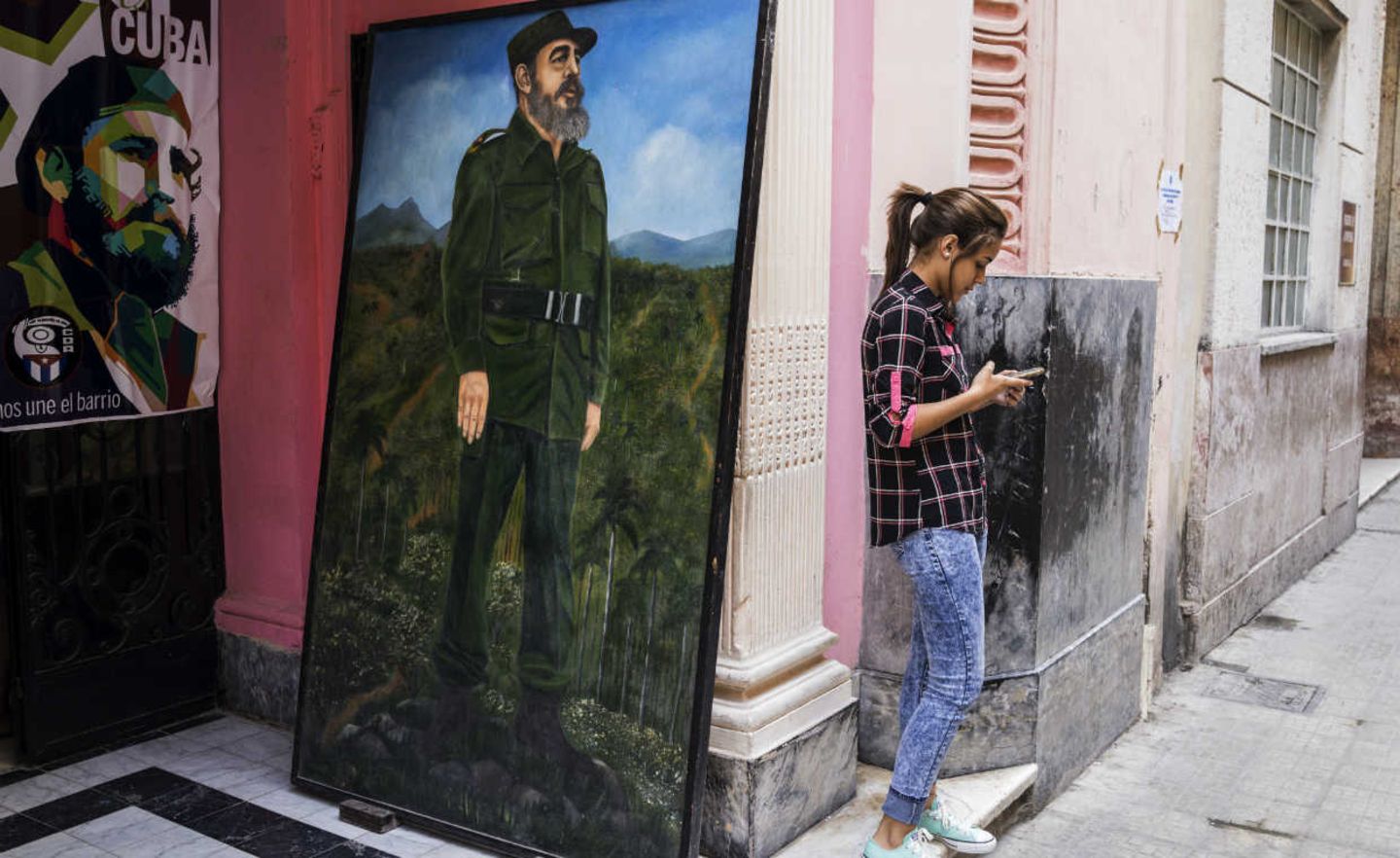Vergangenheit und Zukunft in Havanna: Neben einem Gemälde von Fidel Castro tippt eine junge Frau auf ihrem Smartphone
