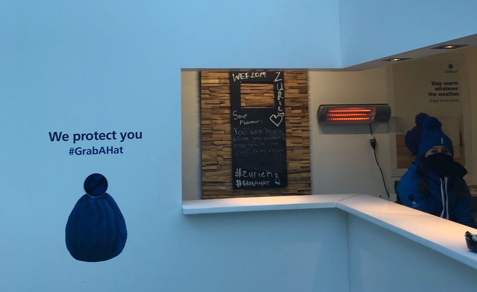 Die Zurich Versicherung hat einen Stand, an dem es warme Getränke gibt und blaue Mützen verschenkt werden – bei im Schnitt minus 15 Grad in Davos eine gute Idee
