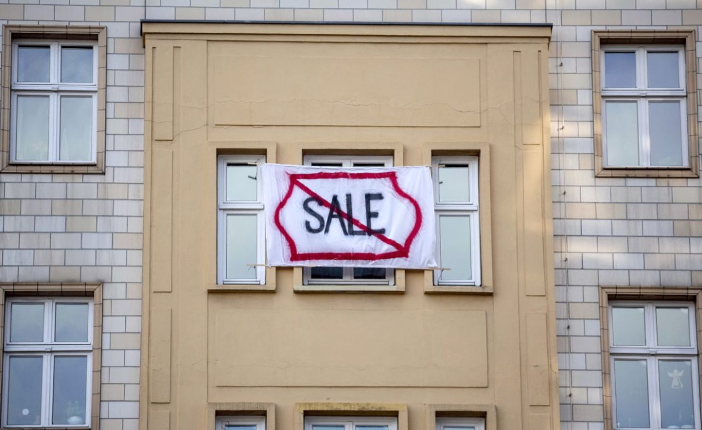 Ein Plakat gegen den Verkauf von Mietwohnungen an die Deutsche Wohnen SE mit dem durchgestrichenen Wort "Sale" hängt an einer Gebäudefassade in der Karl-Marx-Allee. Immer öfter begehren Menschen in Berlin gegen steigende Mieten auf.