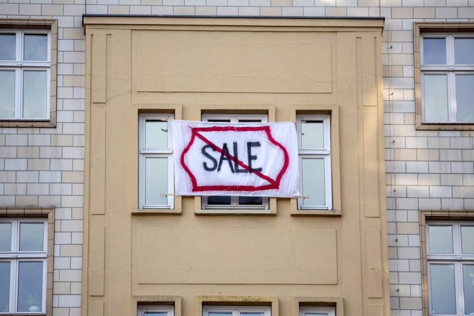 Ein Plakat gegen den Verkauf von Mietwohnungen an die Deutsche Wohnen SE mit dem durchgestrichenen Wort "Sale" hängt an einer Gebäudefassade in der Karl-Marx-Allee. Immer öfter begehren Menschen in Berlin gegen steigende Mieten auf.