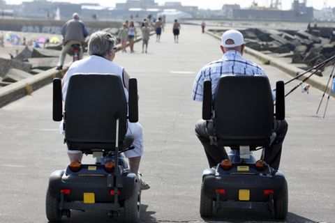 Senioren auf motorisierten Rollstühlen auf einem betonierten Wellenbrecher am Strand von Scheveningen