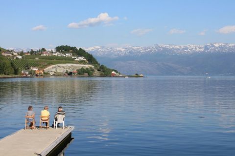 Drei Rentner sitzen am Steg eines Fjordes in Norheimsund, Norwegen