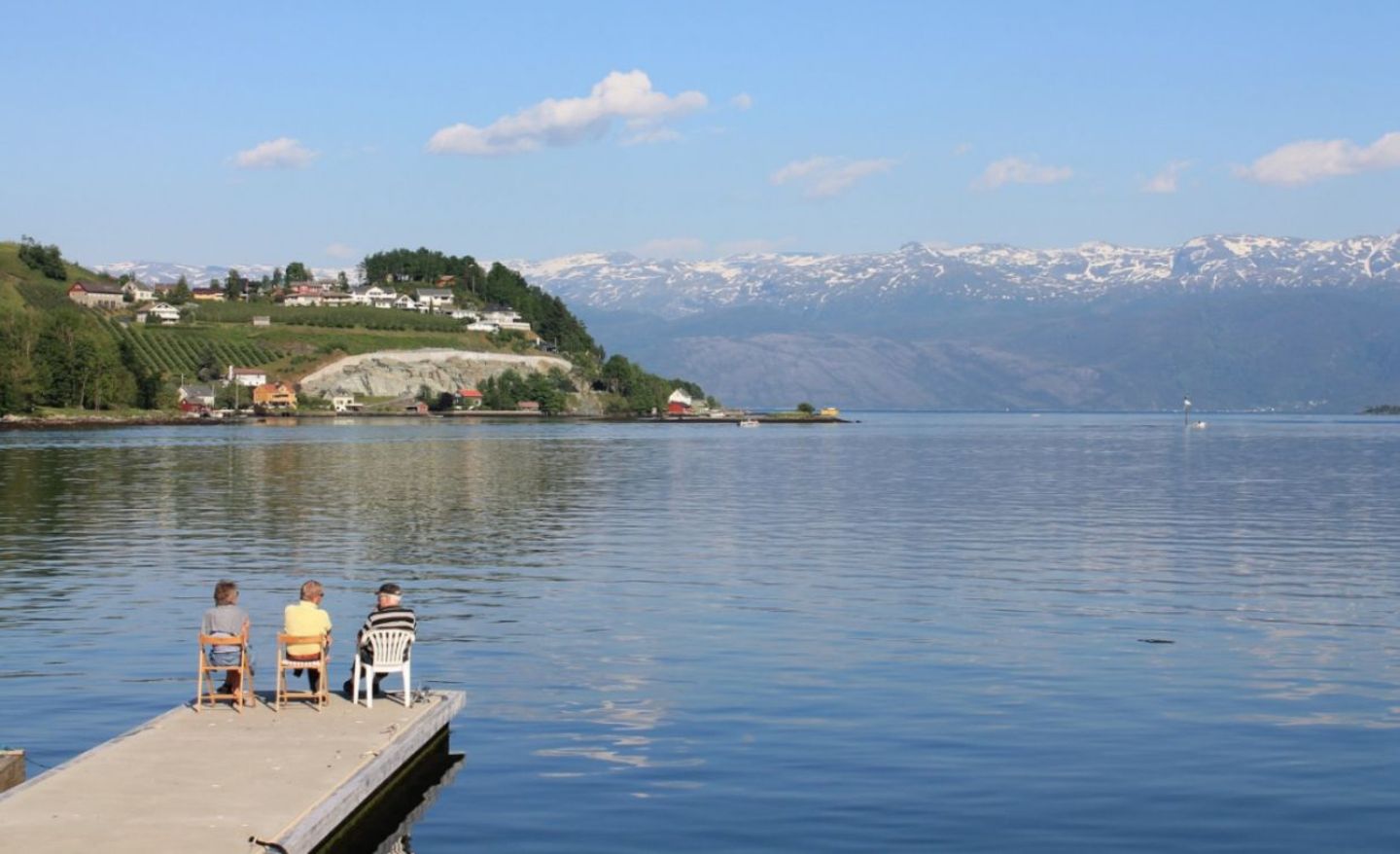 Drei Rentner sitzen am Steg eines Fjordes in Norheimsund, Norwegen