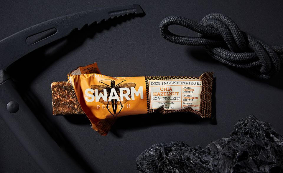 Energieriegel mit Insekten von Swarm Das Kölner Food-Start-up Swarm hat sich ebenfalls auf Lebensmittel aus Insekten spezialisiert, um eine alternative Proteinquelle zu bieten. Sie produzieren Fitnessriegel, die zum Großteil aus Grillen bestehen, die zu einer mehlähnlichen Konsistenz gemahlen und dann zu den Geschmacksrichtungen Frucht, Nuss und Schokolade weiterverarbeitet werden. Die Produktentwicklung dauerte drei Jahre lang, und das Swarm-Team reiste mehrfach nach Thailand in dieser Zeit, denn von dort beziehen sie ihre Grillen. Hinter Swarm stecken die beiden Gründer, Produktdesigner Timo Bäcker und der studierte Betriebswirt und Verhaltensökonom Christopher Zeppenfeld sowie die Ernährungswissenschaftlerin Daniela Falkner, die für ihre Idee im Sommer 2018 mit dem Food Award ausgezeichnet wurden. Die Proteinriegel von Swarm sind bereits in den Supermarktregalen der Hamburger Drogeriemarktkette Budnikowsky, Edeka-Südwest und Rewe-Nord zu finden.