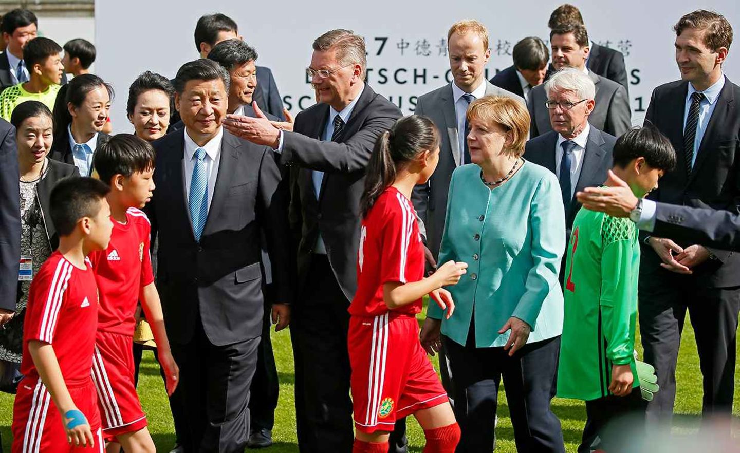 Chinas Präsident Xi Jinping 2017 bei einem Fußballtermin mit Kanzlerin Angela Merkel und dem damaligen DFB-Präsidenten Reinhard Grindel in Berlin: Beide Regierungen haben den Start der Fußballkooperation flankiert