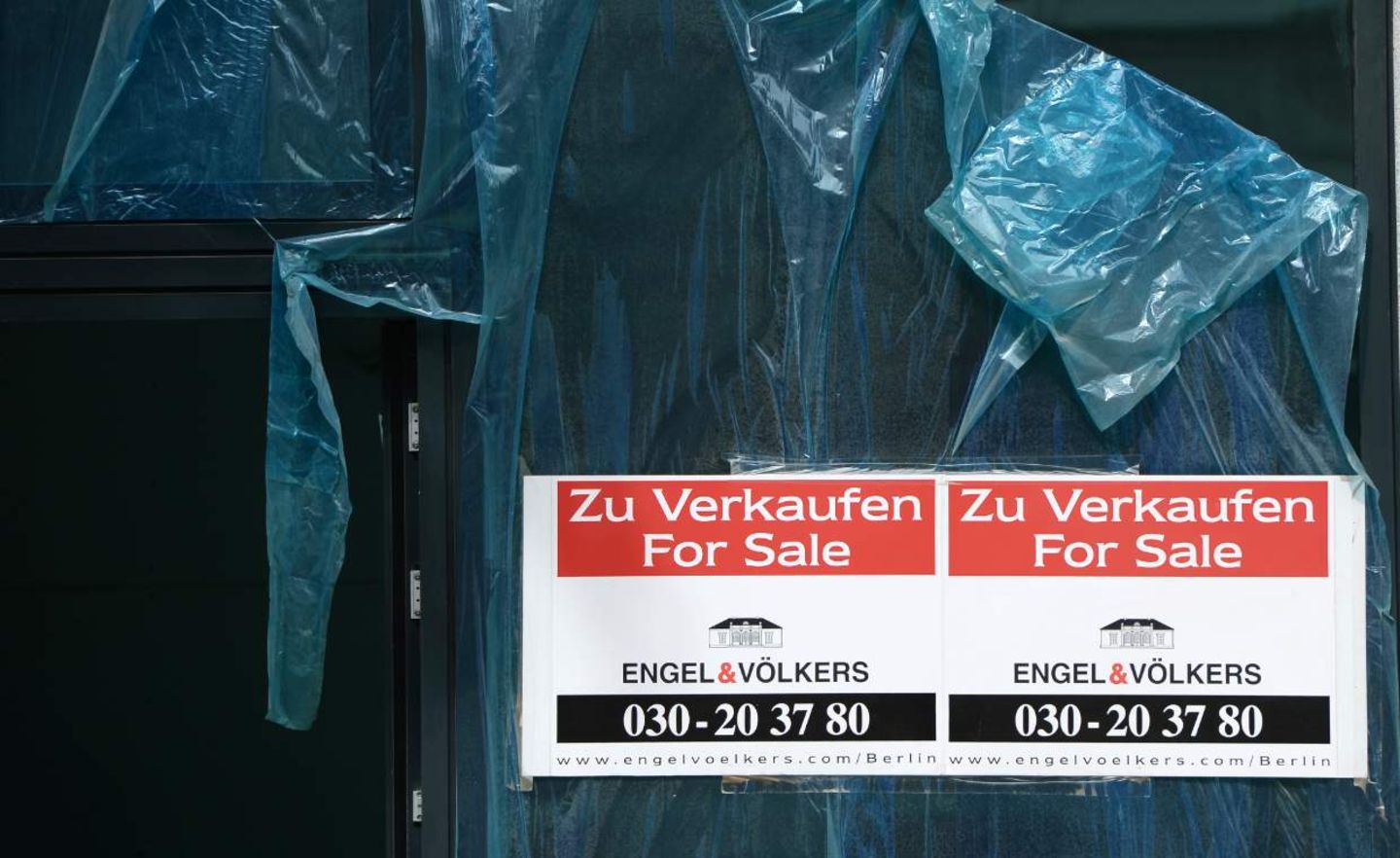 Schilder mit der Aufschrift "Zu Verkaufen - For Sale - Engel & Völkers" hängen an einem neu gebauten Wohnhaus in Berlin