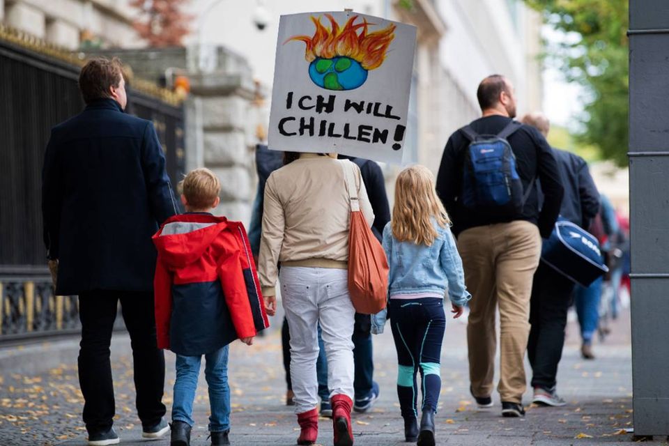 Eine Frau läuft mit zwei Kindern und einem Schild auf dem Rücken zu einer Demonstration zum globalen Klimastreik, zu dem die Bewegung Fridays for Future aufgerufen hat