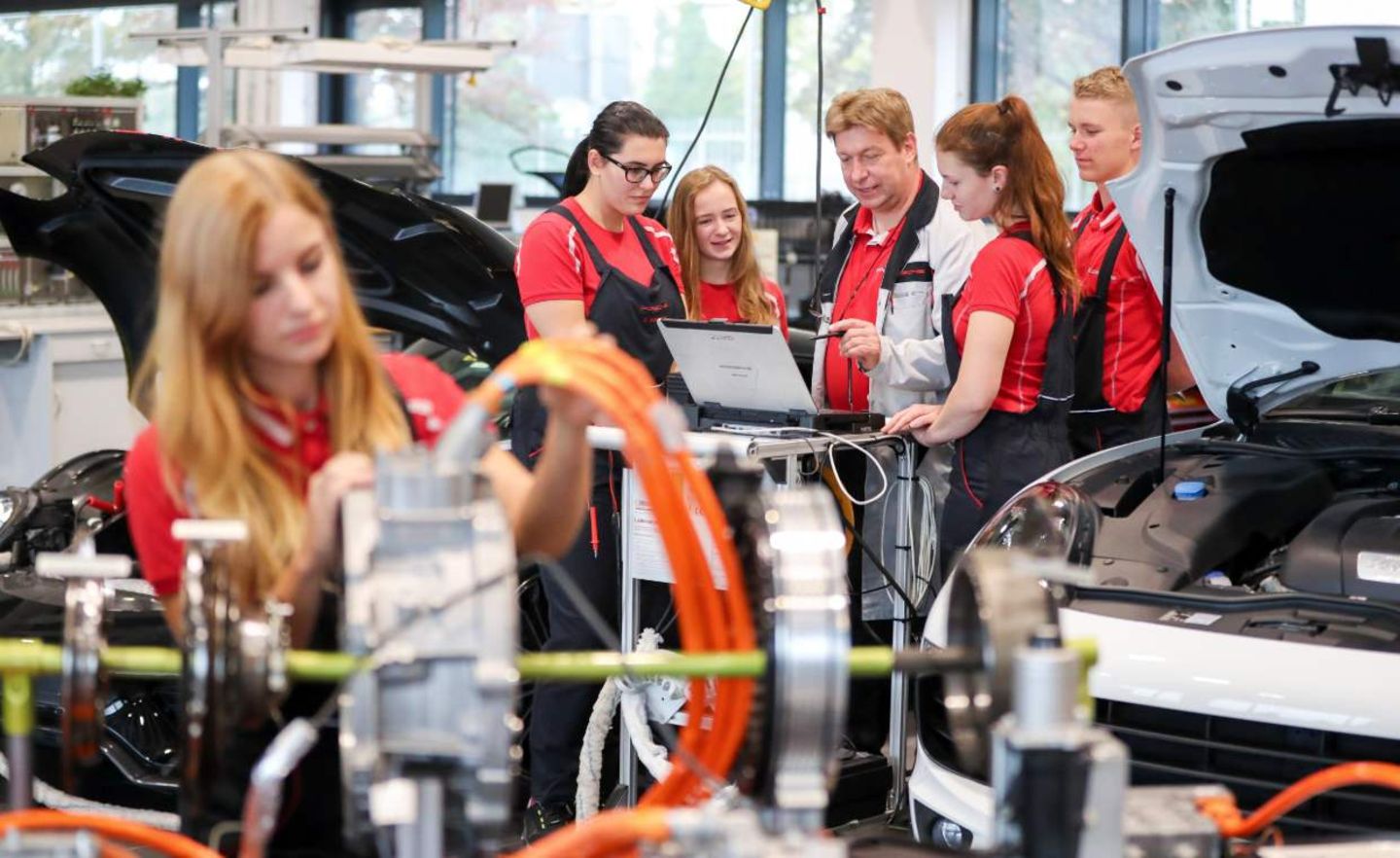 Ein Ausbilder erläutert Auszubildenden im 2. Lehrjahr die Funktionsweise eines Hybridantriebes im Porsche Ausbildungszentrum