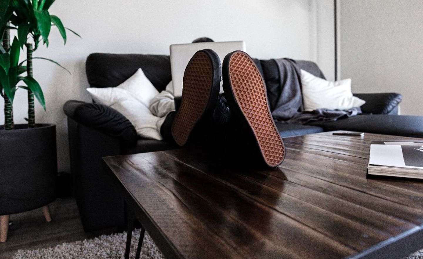 Person mit Laptop auf Sofa