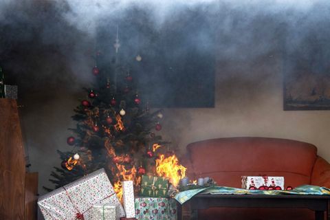 Ein brennender Weihnachtsbaum steht während einer Vorführung in einem nachgebauten Wohnzimmer. Die Feuerwehr informiert über die Gefahren zu Weihnachten