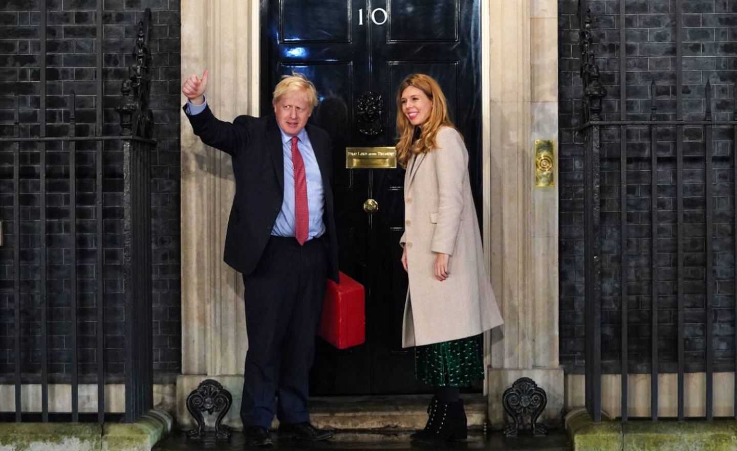 Boris Johnson winkt vor der Tür des Regierungssitzes in der Downing Street. Neben ihm steht seine Partnerin Carrie Symonds