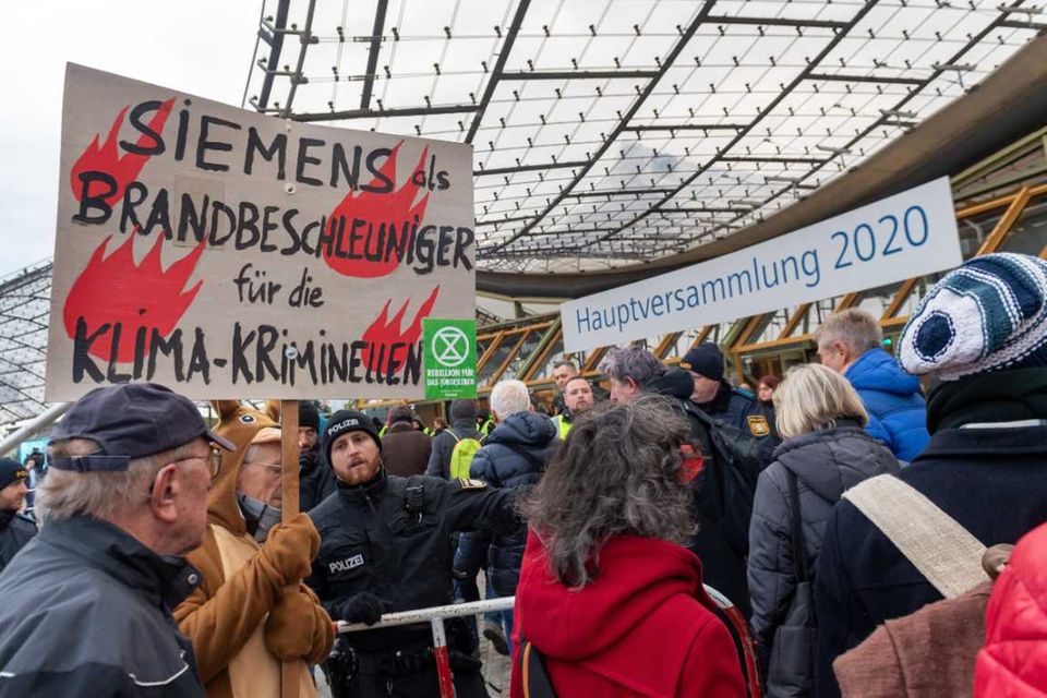 Vor der Halle der Siemens-Hauptversammlung demonstrieren Hunderte Umweltaktivisten und fordern einen Ausstieg aus dem Geschäft mit Kohle-, Öl- und Gaskraftwerken.