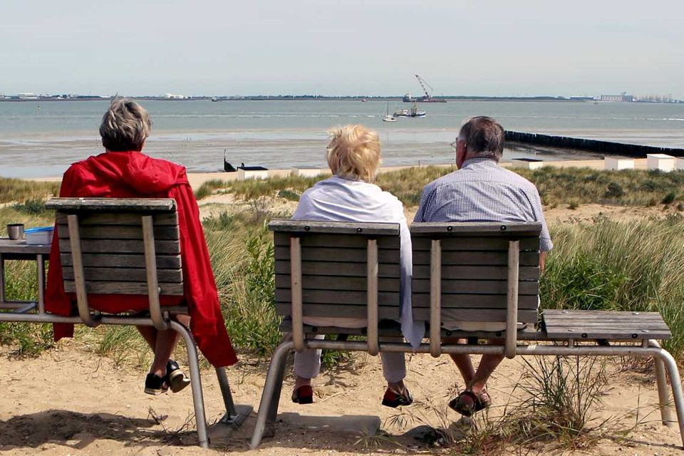 Rentner sitzen auf einer Bank und schauen aufs Meer