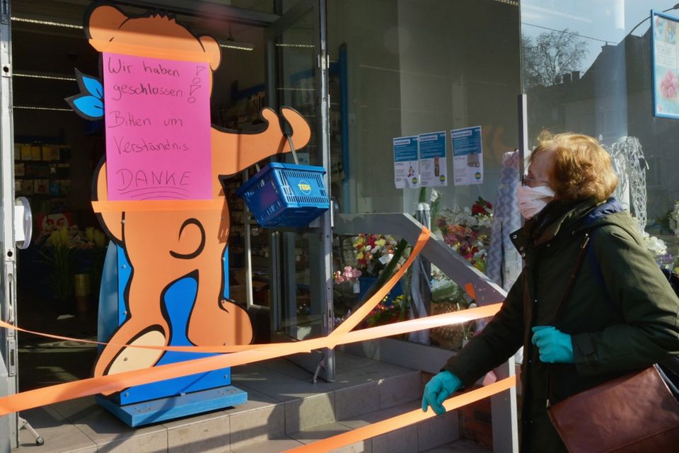 Eine Kundin mit Mundschutz steht vor einem geschlossens TEDI Einzelhandelgeschäft