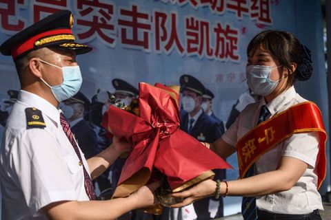 Blumen für chinesische Zugfahrer, die im südchinesischen Guilin Sonderschichten Schutzausrüstung transportieren.