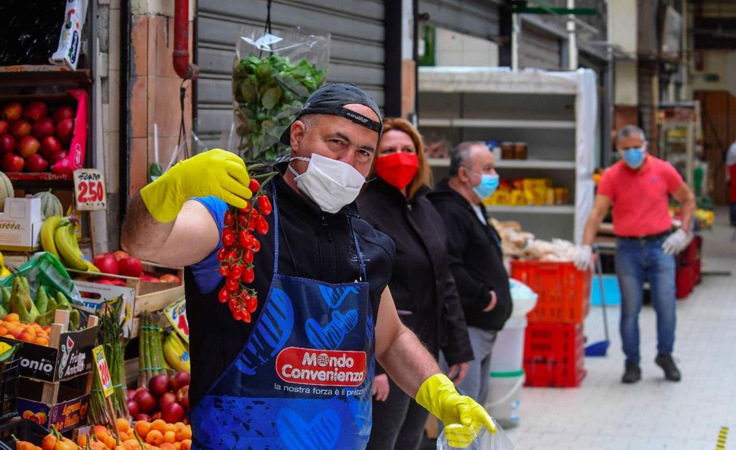 Ein italienischer Händler hält eine Rispe Tomaten hoch. Der Markt für Produzenten aus der Region darf im Rahmen der Covid-19-Lockerungen seit kurzem wieder öffnen.