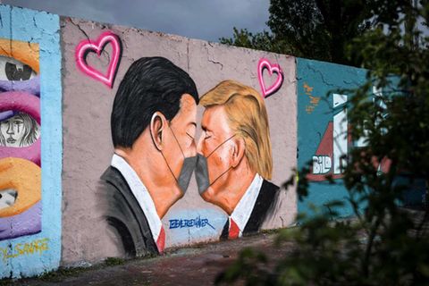 Chinas Staatschef Xi Jinping (l.) und US-Präsident Donald Trump sind auf einem Graffitto des Straßenkünstlers Eme Freethinker küssend und mit Mundschutz zu sehen