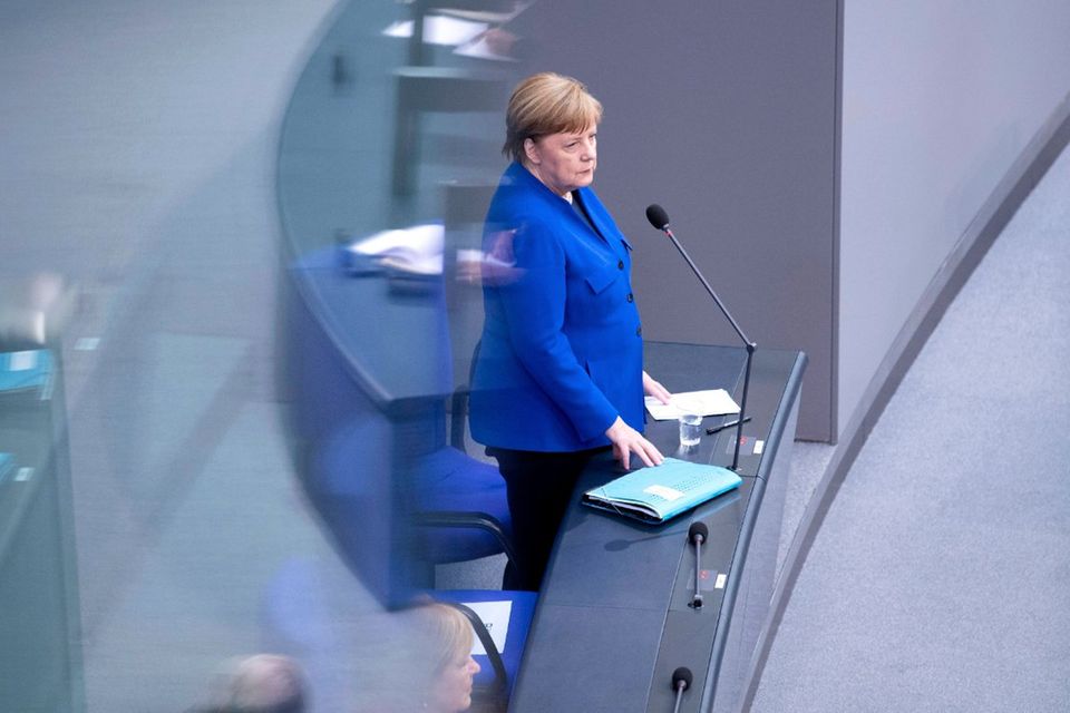 Bundeskanzlerin Angela Merkel steht an ihrem Platz während der Debatte zur Corona-Pandemie im Bundestag