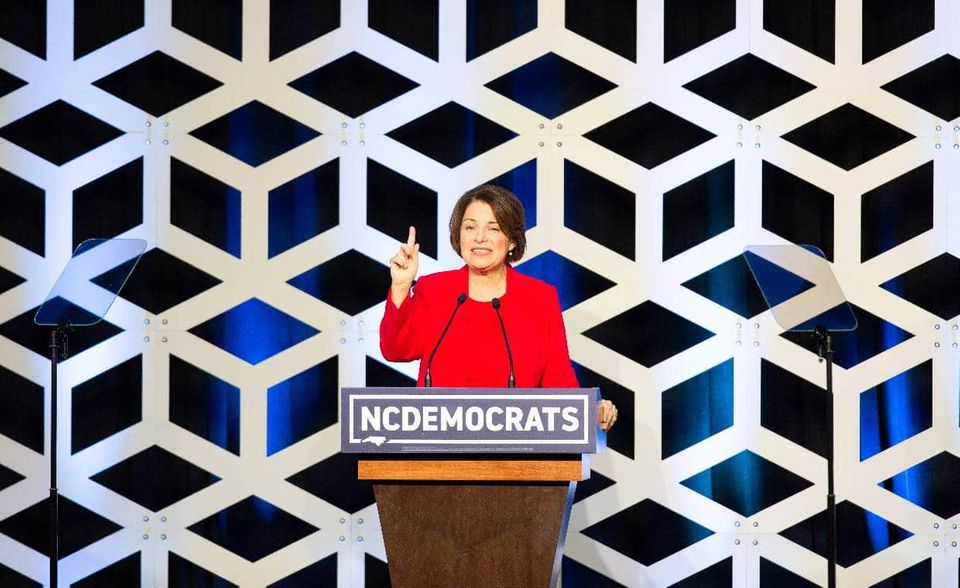 Auch Amy Klobuchar gehört als Senatorin von Minnesota dem Senat an – und auch sie bewarb sich um die Präsidentschaftskandidatur der Demokraten. Mit einigen Positionen aus ihrem Wahlprogramm setzte sie sich für eine linksliberal gerichtete Politik ein, so befürwortete sie etwa die Abschaffung von Studiengebühren, den Ausbau erneuerbarer Energien und die Abschaffung der Todesstrafe. Dennoch gilt sie bei den Demokraten als Pragmatikerin der Mitte. Eine vollkommen kostenfreie Hochschulbildung lehnt sie etwa ab, eine gesetzliche Krankenversicherung ebenso.