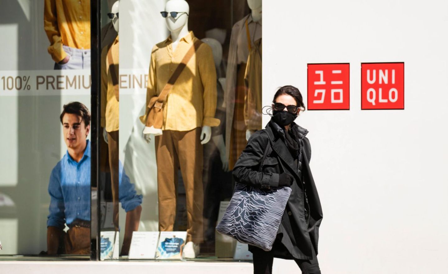 Eine Frau mit Mundschutz geht an einem Uniqlo-Geschäft vorbei