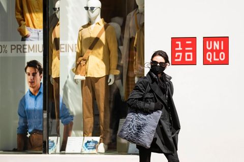 Eine Frau mit Mundschutz geht an einem Uniqlo-Geschäft vorbei