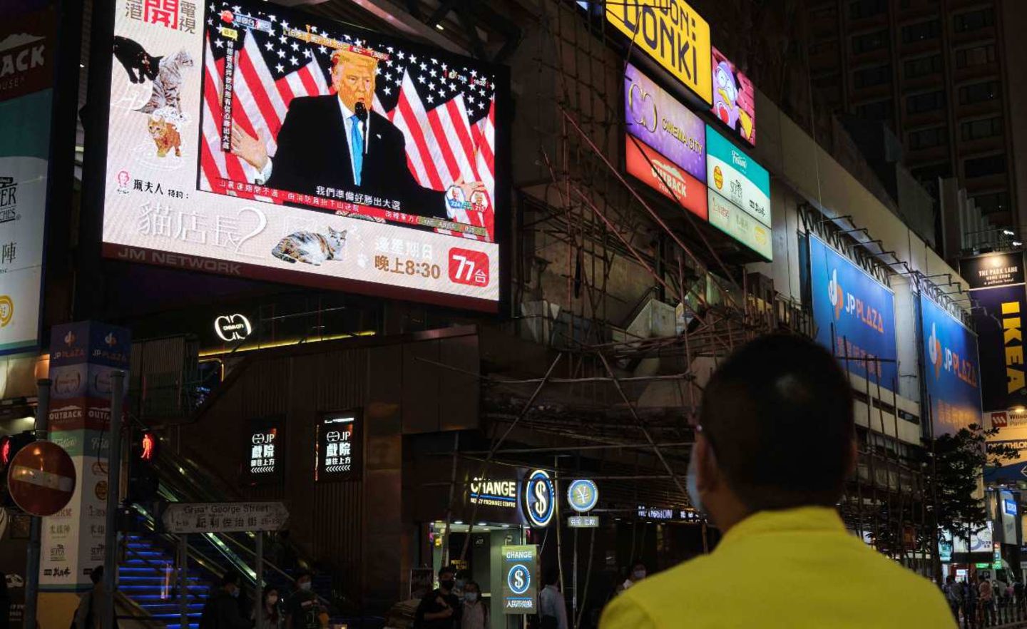 Ein Mann in Hongkong schaut sich auf einem Großbildschirm ein Statement von Donald Trump an