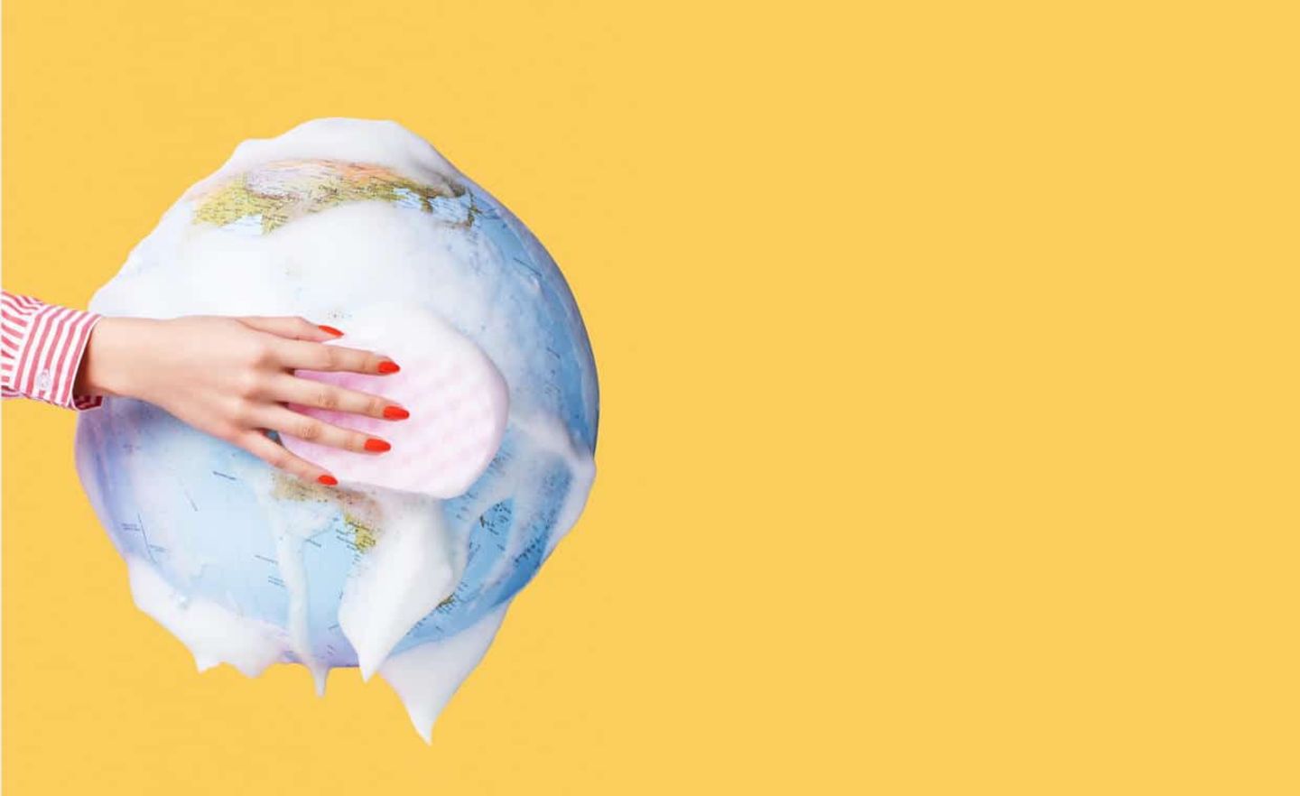 Still life image of a globe being washed by a hand with a sponge to symbolise cleaning and saving the planet.