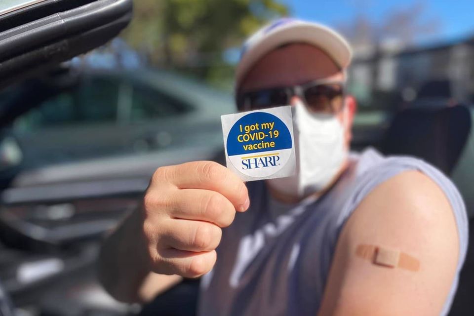 Ein Helfer aus Kalifornien zeigt stolz einen Sticker auf dem steht, dass er gegen Covid-19 geimpft wurde