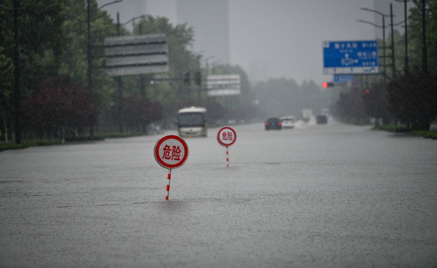 Warnschilder auf einer überfluteten Allee der Provinzhauptstadt Zhengzhou.