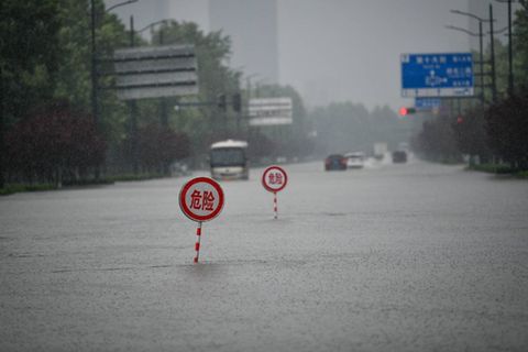 Warnschilder auf einer überfluteten Allee der Provinzhauptstadt Zhengzhou.