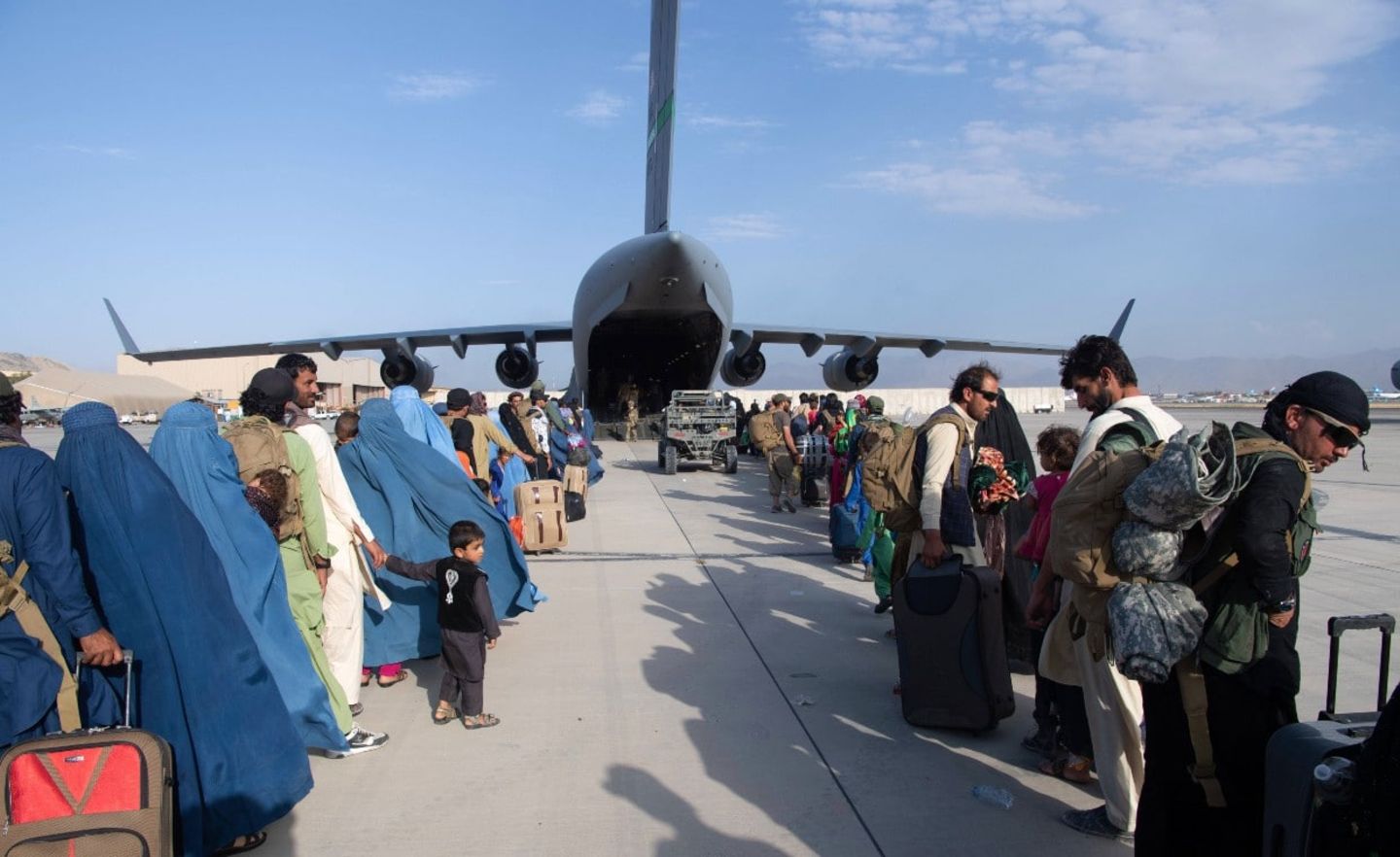Afghanische Flüchtlinge warten vor einem Militärtransportflugzeug, das sie in Sicherheit bringen soll