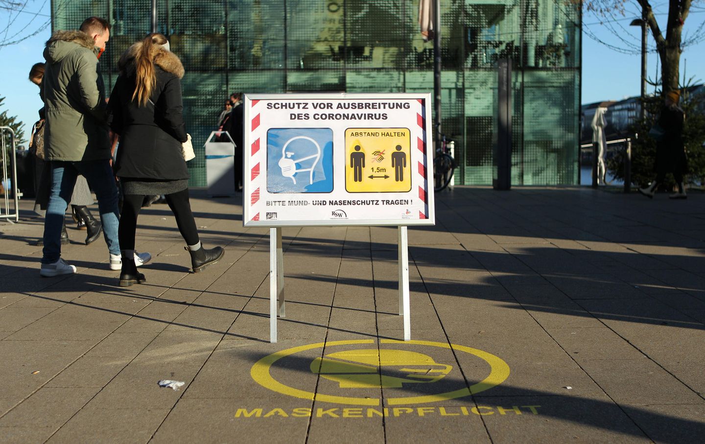 Ein Aufsteller auf dem Jungfernstieg auf dem Weihnachtsmarkt weist Besucher darauf hin, dass hier Maskenpflicht besteht und ein Mindestabstand von 1,5 Meter einzuhalten ist