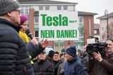 Nicht alle Brandenburger sind glücklich über die Ansiedlung von Tesla in der Nachbarschaft: Es gibt Demonstrationen, Plakate werden aufgehängt. Die Kritik der Demonstrierenden: Für die Fabrik würden große Flächen Wald gerodet, außerdem könnte die Trinkwasserversorgung beeinträchtigt werden.
